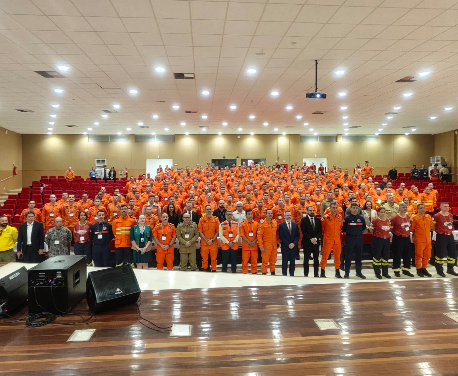 bombeiros em pé pousando para foto em auditório